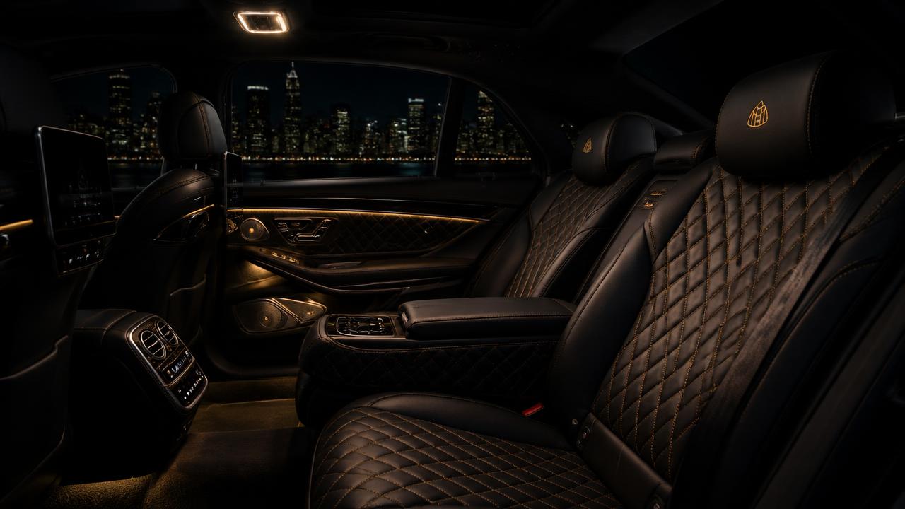 Rear cabin of a chauffeured luxury car at night with city lights outside